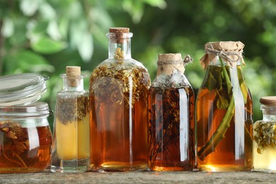 Photo of Different natural tinctures on wooden table outdoors, closeup