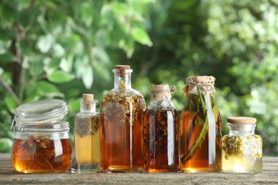 Photo of Different natural tinctures on wooden table outdoors