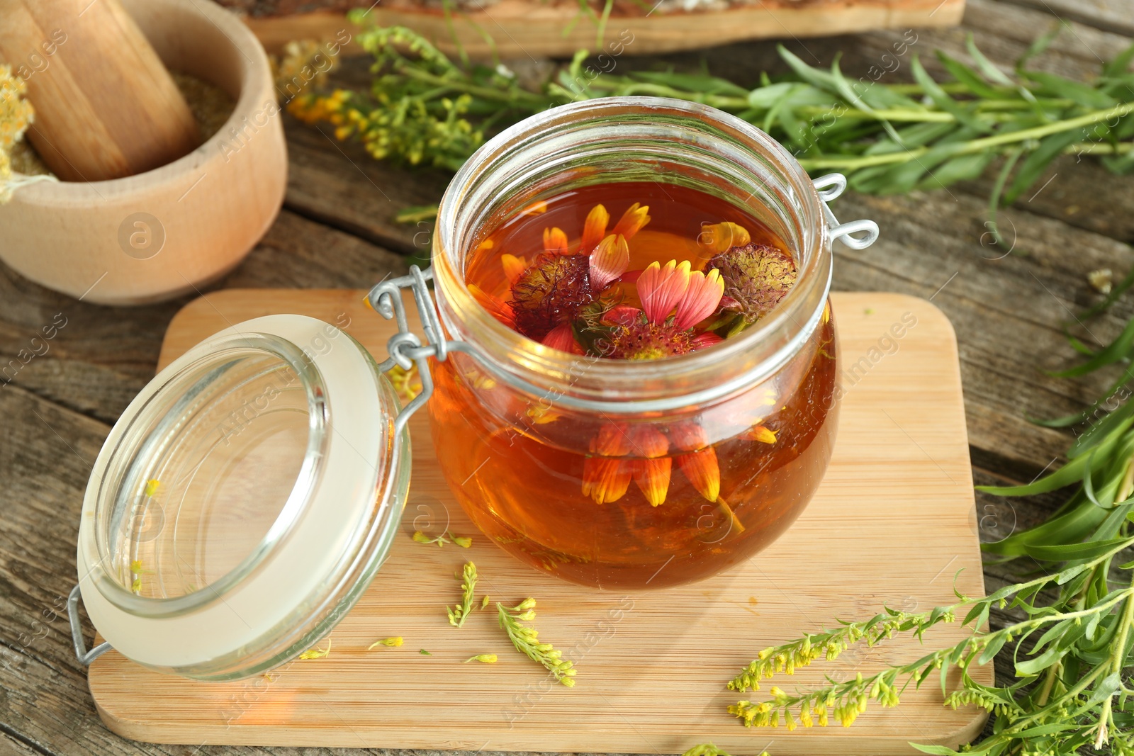 Photo of Natural tincture in jar with flowers and herbs on wooden table