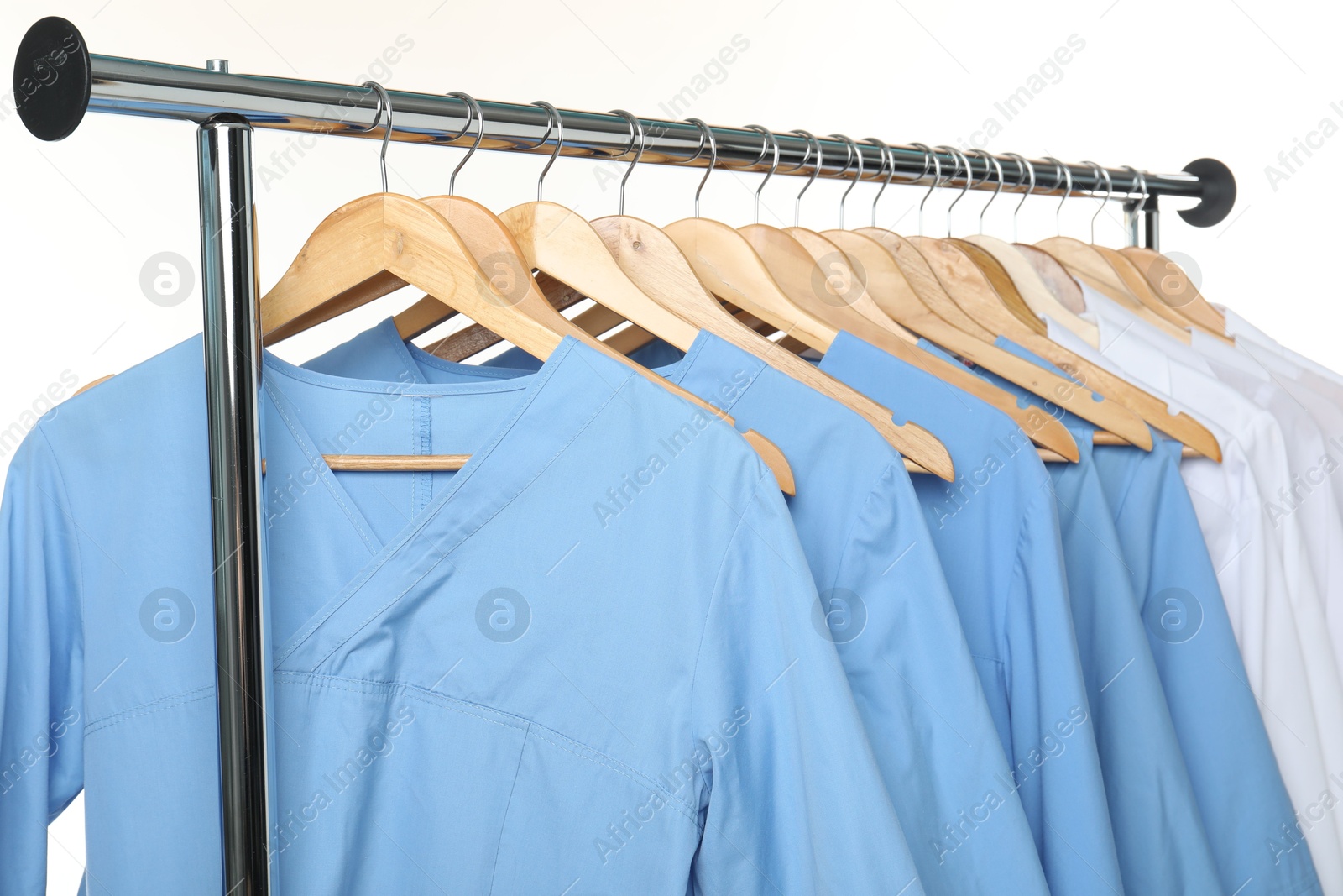 Photo of Different medical workers' uniforms on clothing rack against white background