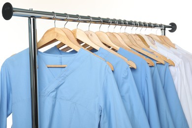 Photo of Different medical workers' uniforms on clothing rack against white background