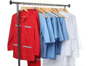 Different medical workers' uniforms on clothing rack against white background