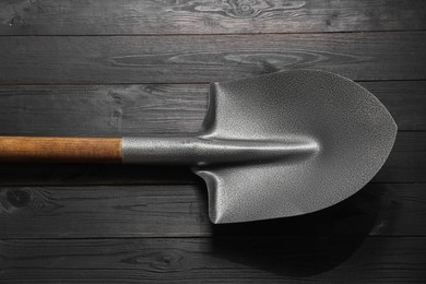 Photo of Metal shovel on black wooden table, top view