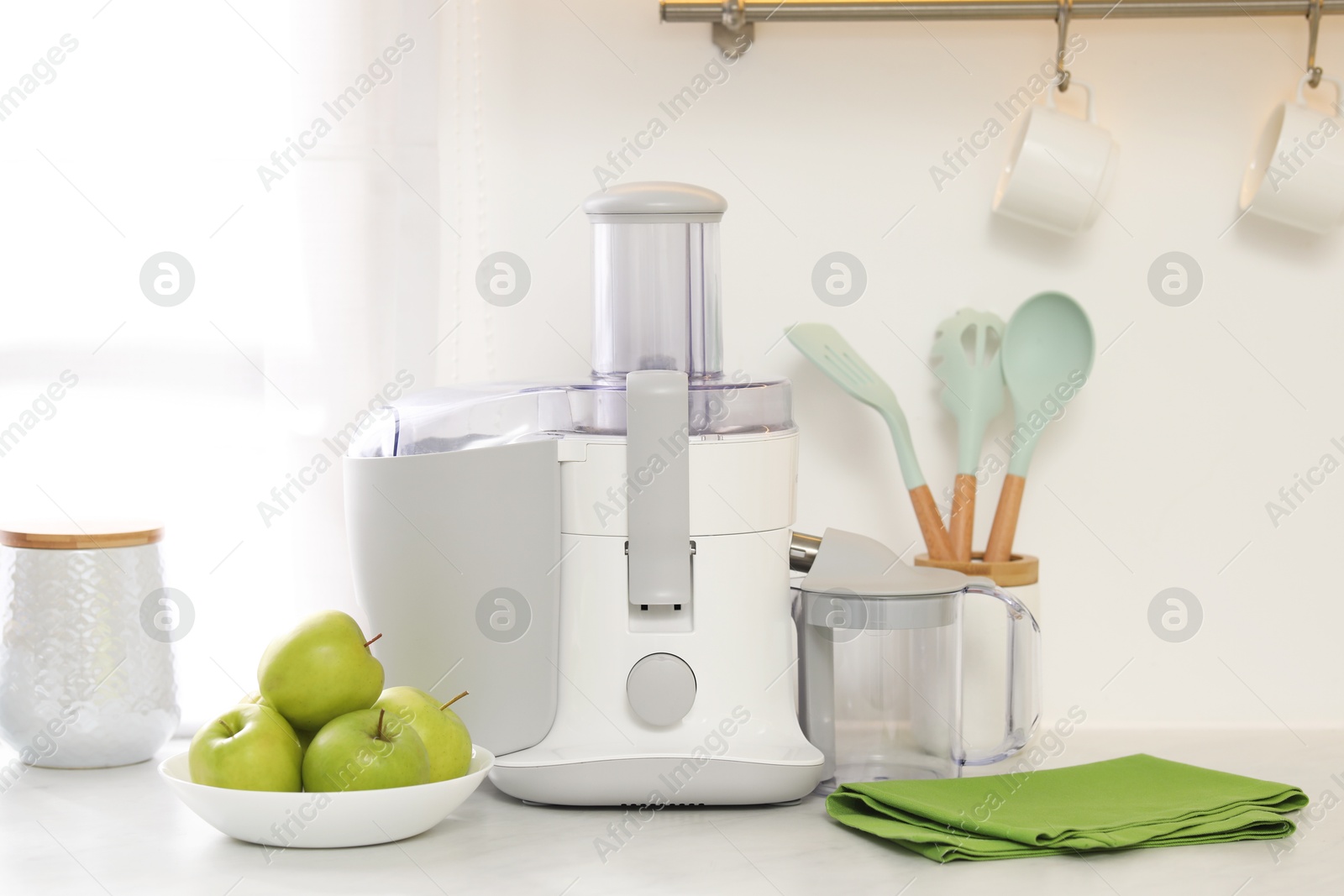 Photo of Modern juicer and apples on white counter in kitchen