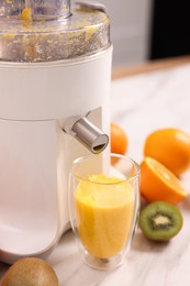 Modern juicer, fresh fruits and glass on white marble table in kitchen, closeup