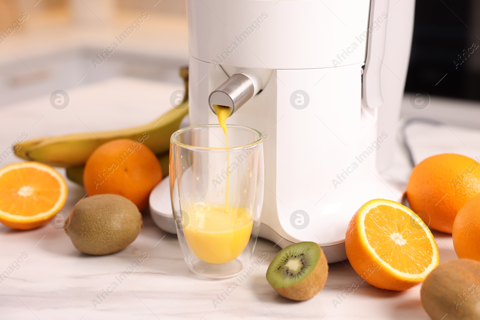 Photo of Modern juicer, fresh fruits and glass on white marble table in kitchen, closeup