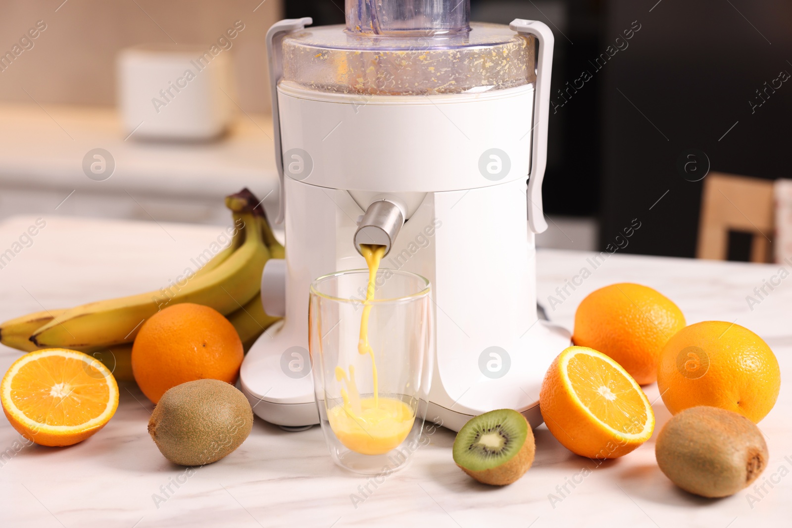 Photo of Modern juicer, fresh fruits and glass on white marble table in kitchen, closeup