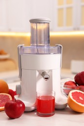 Photo of Modern juicer, fresh fruits and glass on white marble table in kitchen