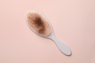 Photo of One brush with lost hair on light pink background, top view