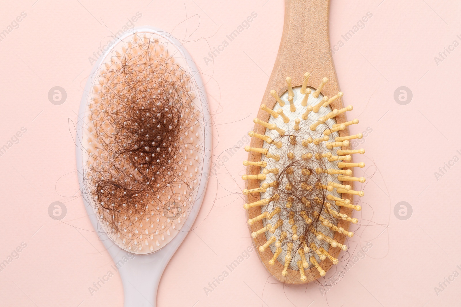 Photo of Brushes with lost hair on light pink background, flat lay