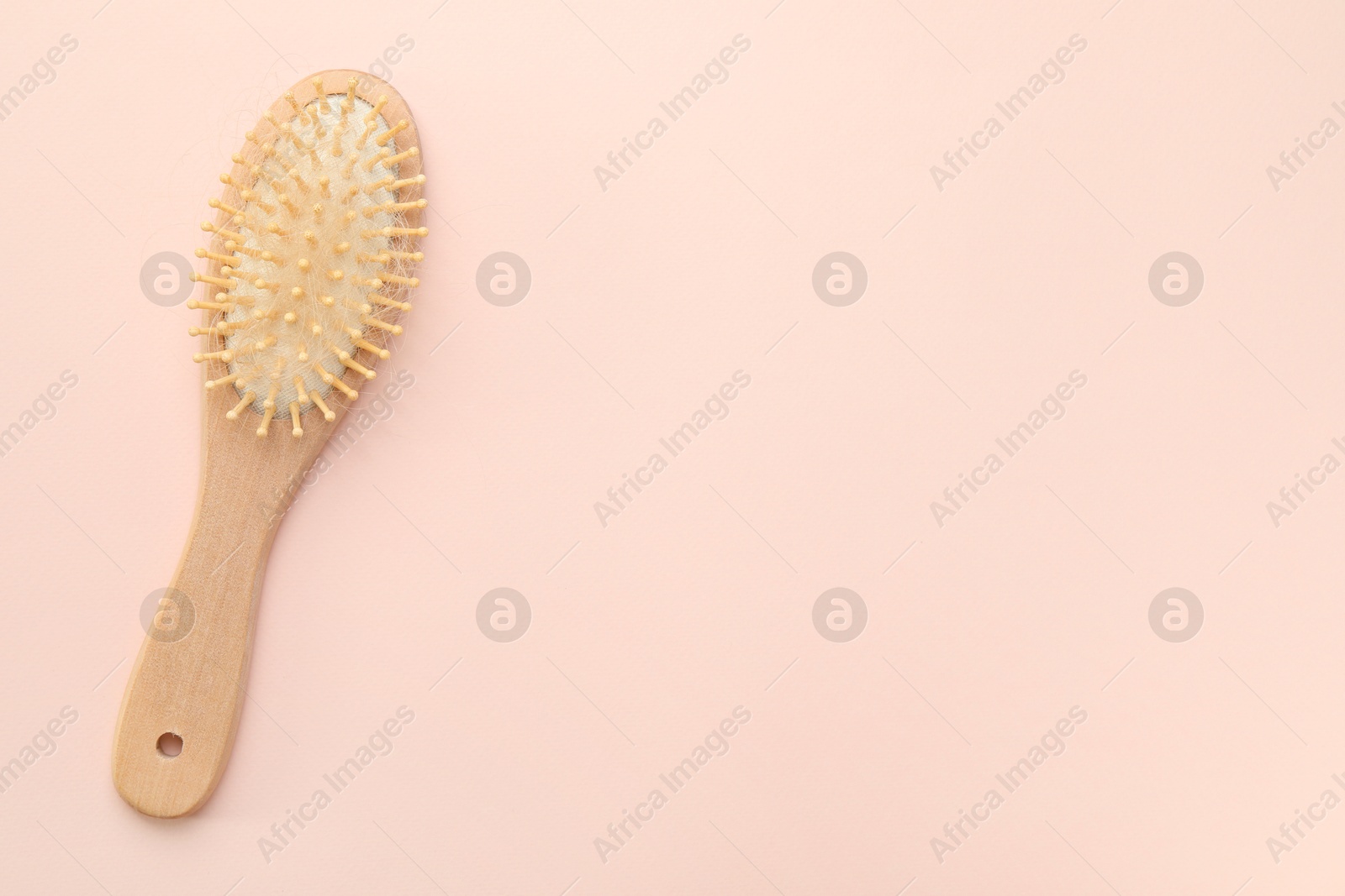 Photo of One brush with lost hair on light pink background, top view. Space for text