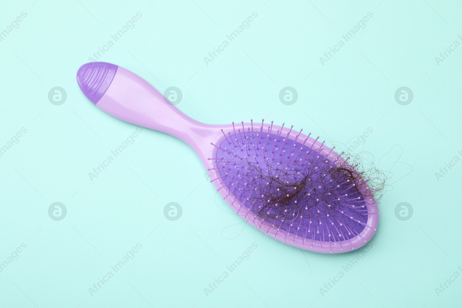 Photo of One brush with lost hair on light blue background, top view. Alopecia problem