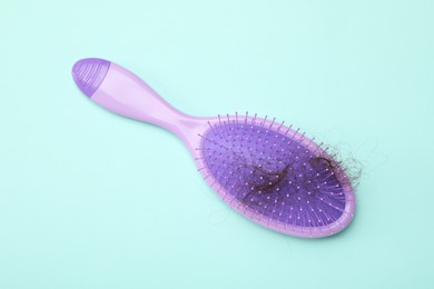 One brush with lost hair on light blue background, top view. Alopecia problem