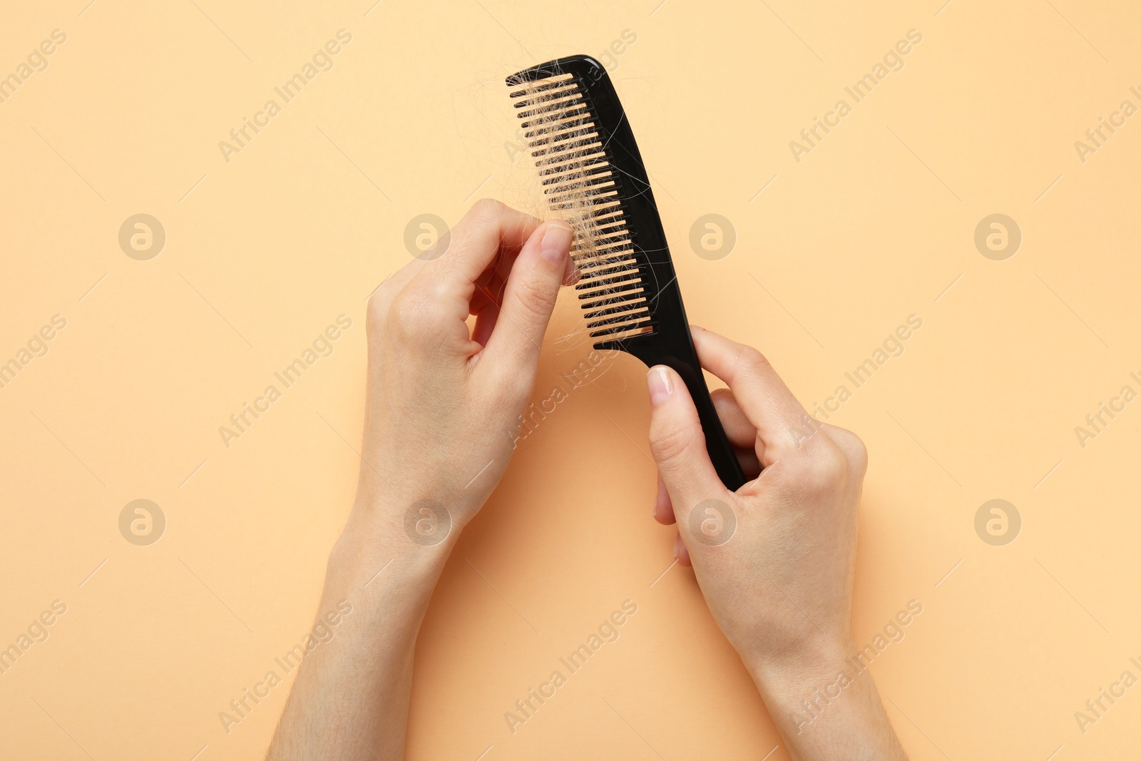 Photo of Woman taking her lost hair from comb on coral background, top view. Alopecia problem