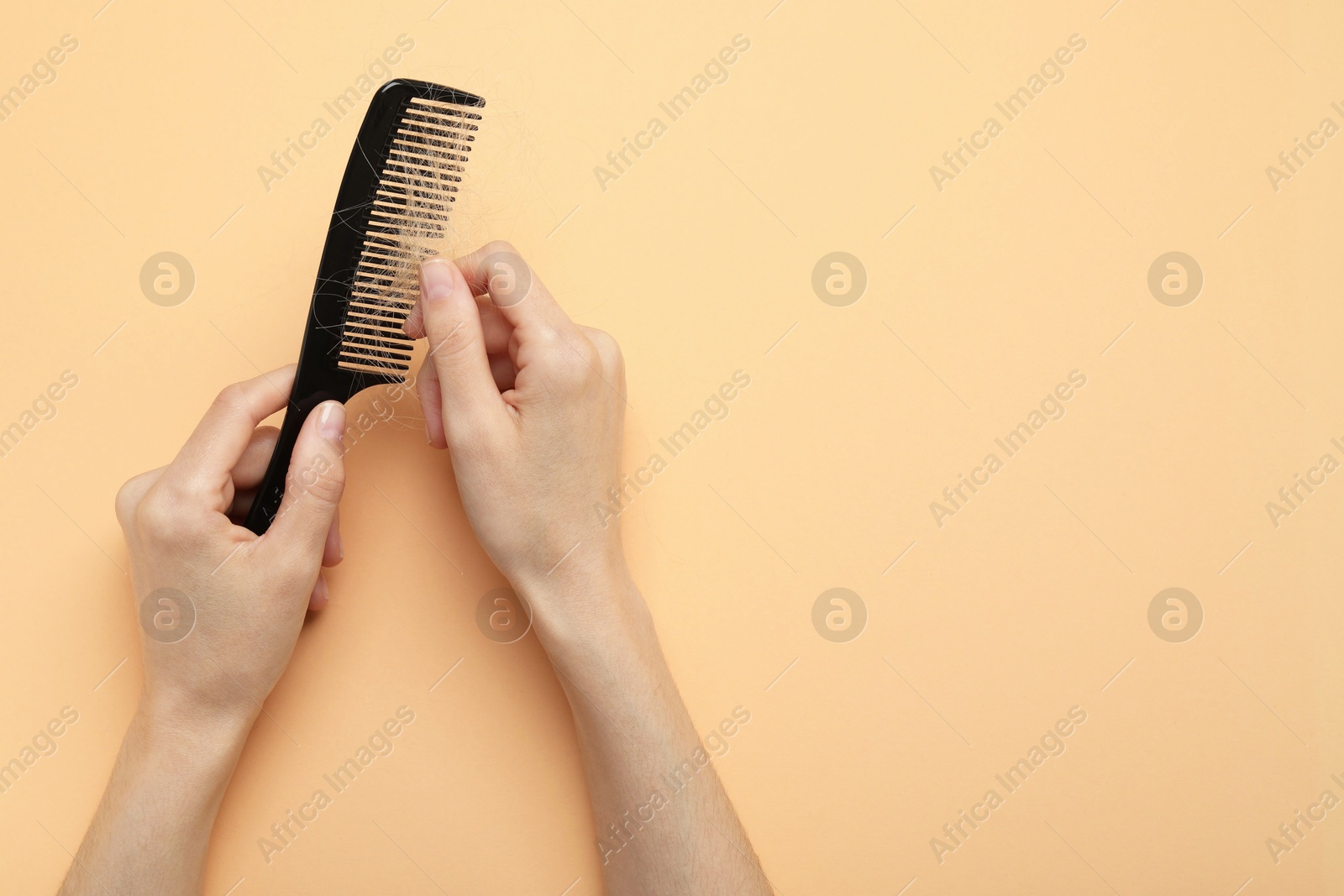 Photo of Woman taking her lost hair from comb on coral background, top view. Space for text