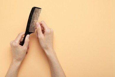 Woman taking her lost hair from comb on coral background, top view. Space for text