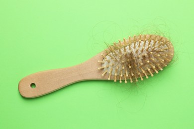 One brush with lost hair on light green background, top view. Alopecia problem