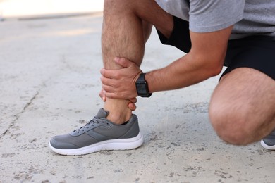 Photo of Man suffering from foot pain outdoors, closeup