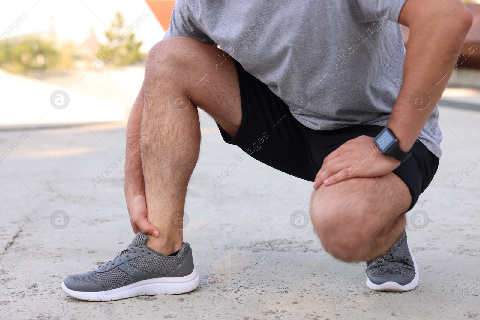 Photo of Man suffering from foot pain outdoors, closeup