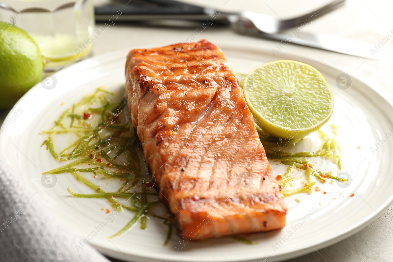 Photo of Delicious grilled salmon fillet served on light table, closeup