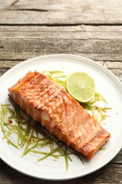 Photo of Delicious grilled salmon fillet served on wooden table, closeup