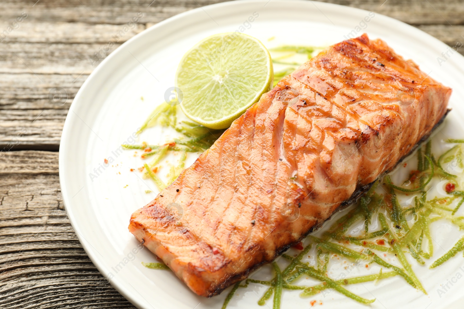 Photo of Delicious grilled salmon fillet served on wooden table, closeup