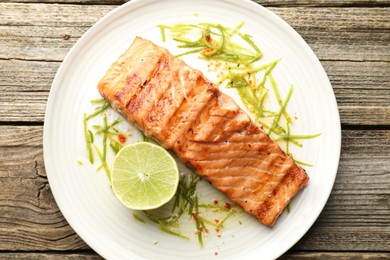 Photo of Delicious grilled salmon fillet served on wooden table, top view