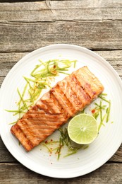 Photo of Delicious grilled salmon fillet served on wooden table, top view