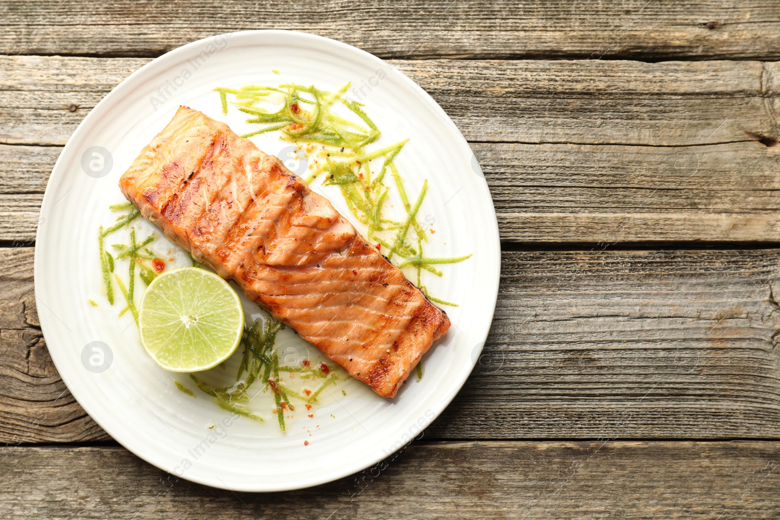 Photo of Delicious grilled salmon fillet served on wooden table, top view