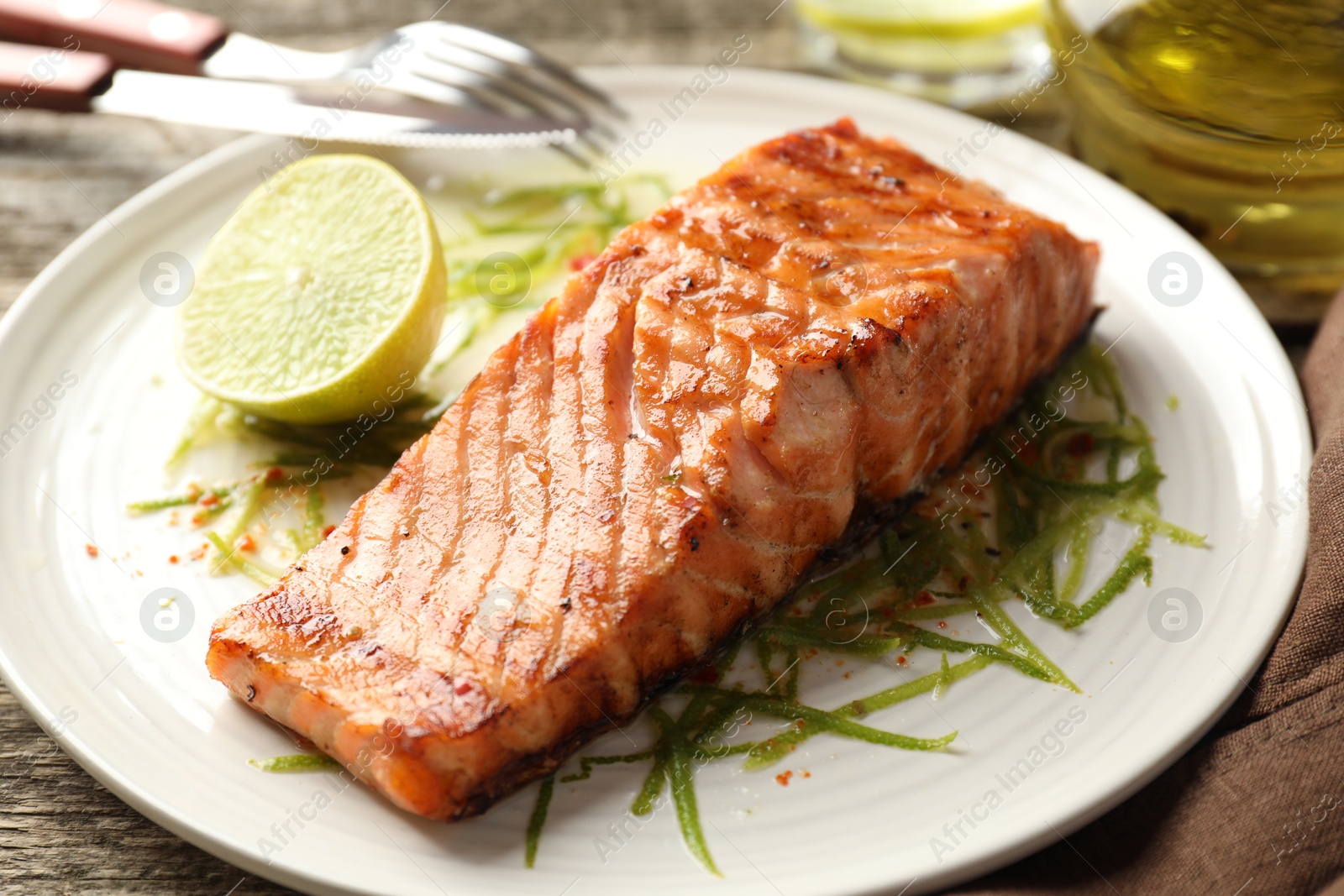 Photo of Delicious grilled salmon fillet served on wooden table, closeup