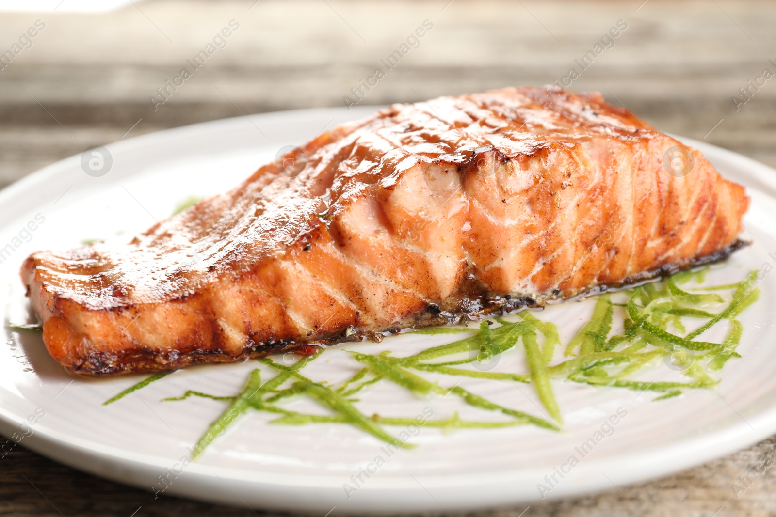 Photo of Delicious grilled salmon fillet served on wooden table, closeup