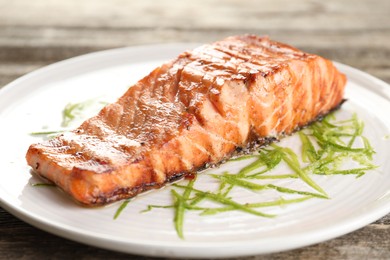 Photo of Delicious grilled salmon fillet served on wooden table, closeup