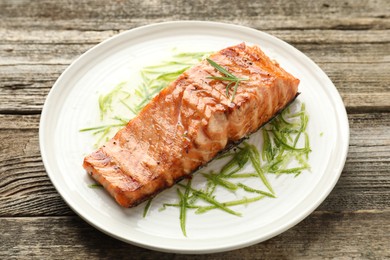 Delicious grilled salmon fillet served on wooden table, closeup