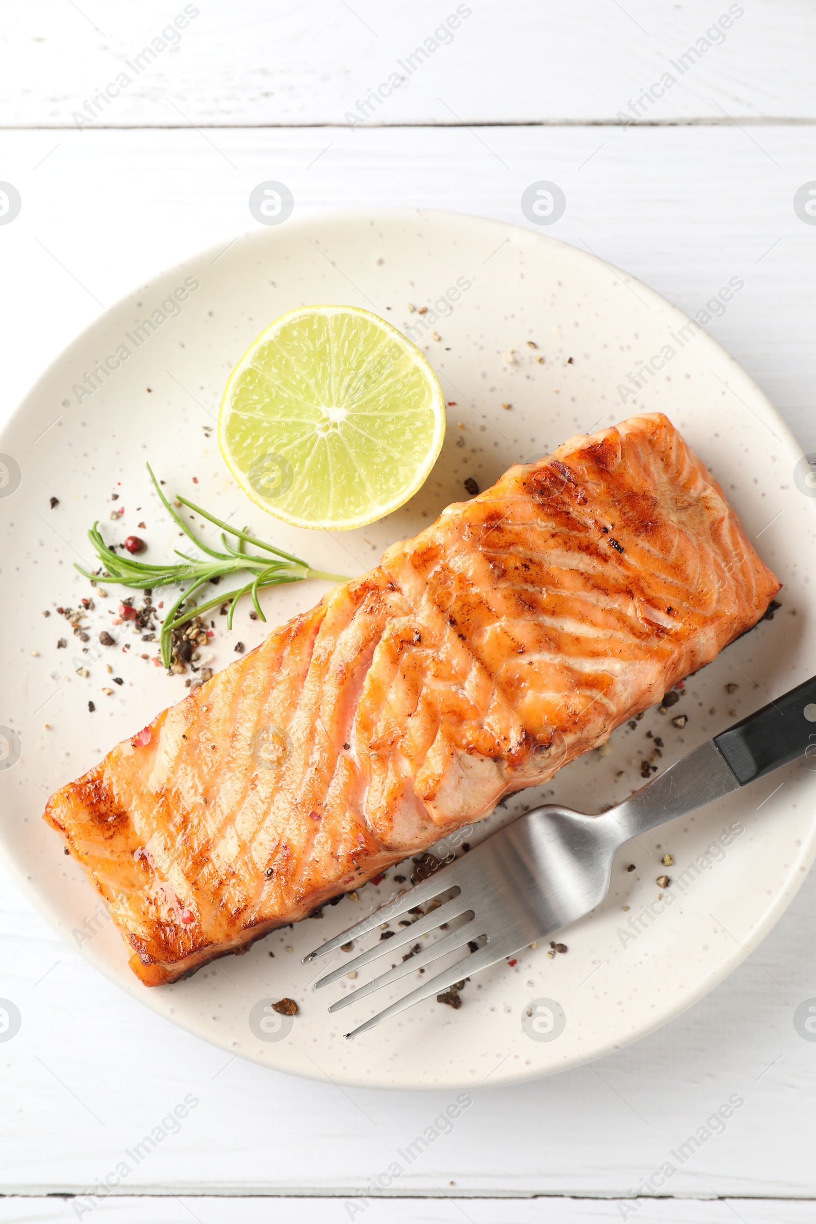 Photo of Delicious grilled salmon fillet served on white wooden table, top view