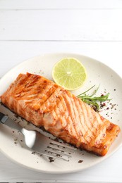 Delicious grilled salmon fillet served on white wooden table, closeup