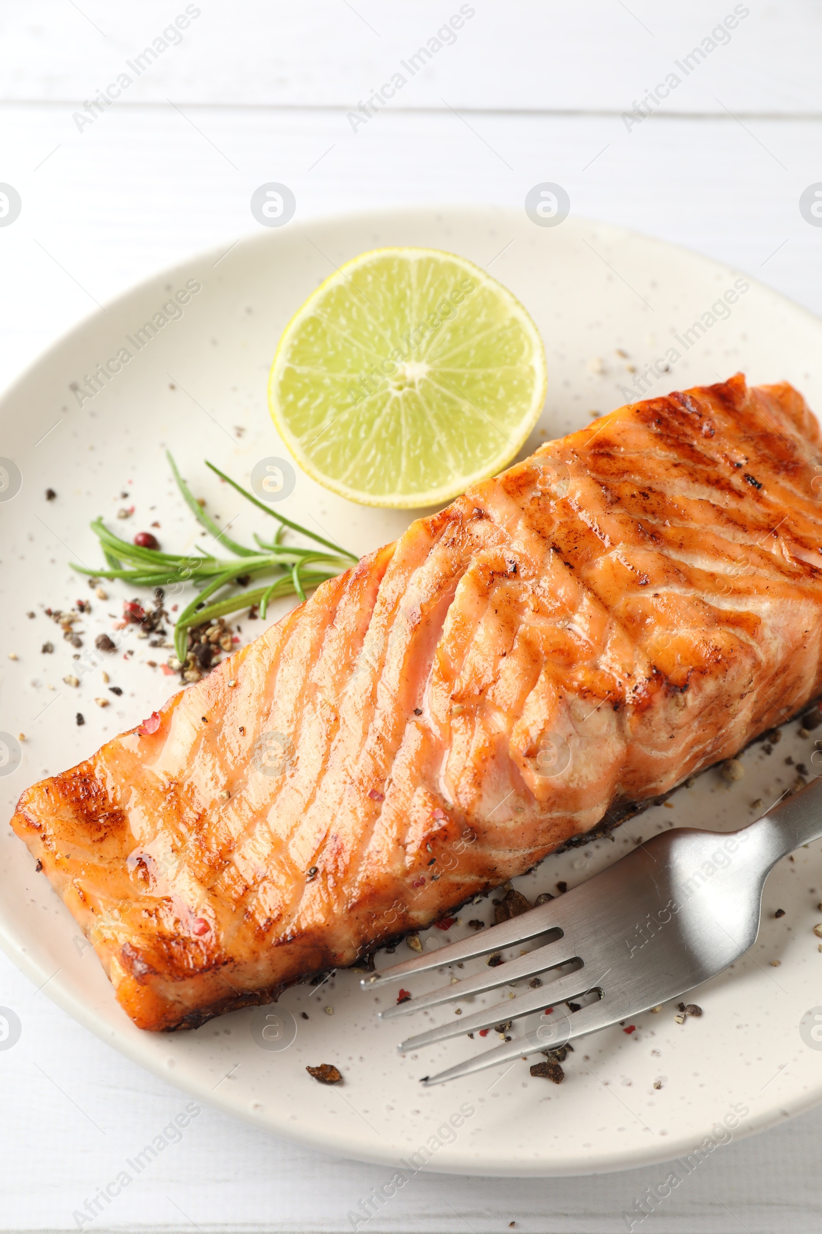 Photo of Delicious grilled salmon fillet served on white wooden table, closeup