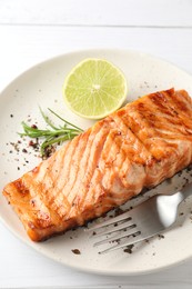 Photo of Delicious grilled salmon fillet served on white wooden table, closeup