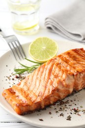 Delicious grilled salmon fillet served on white wooden table, closeup