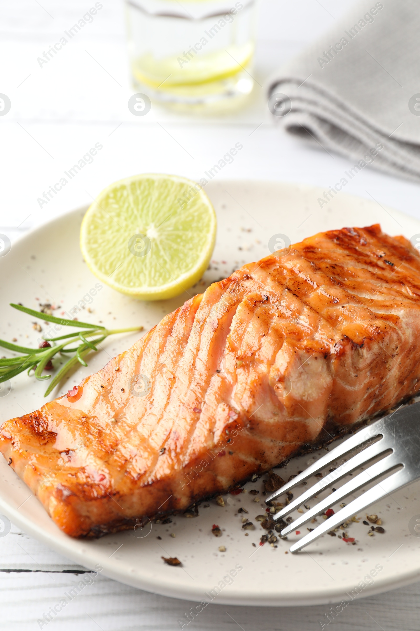 Photo of Delicious grilled salmon fillet served on white wooden table, closeup