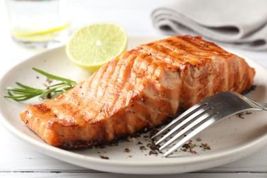 Delicious grilled salmon fillet served on white wooden table, closeup