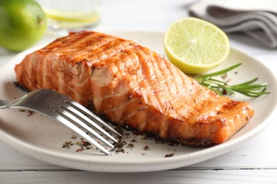 Delicious grilled salmon fillet served on white wooden table, closeup