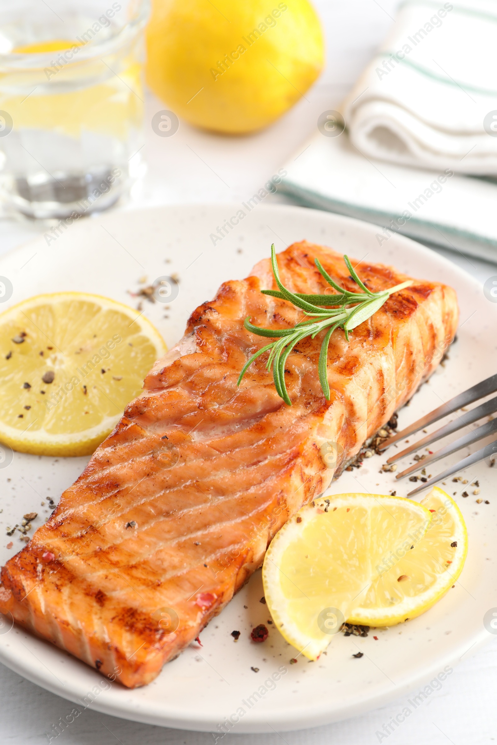 Photo of Delicious grilled salmon fillet served on white table, closeup