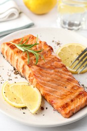 Photo of Delicious grilled salmon fillet served on white table, closeup