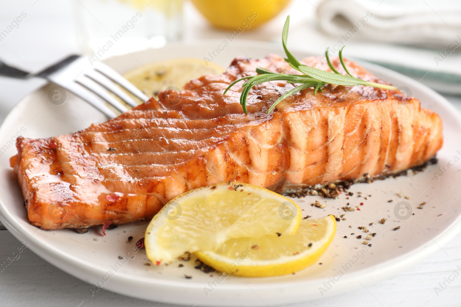 Photo of Delicious grilled salmon fillet served on white table, closeup