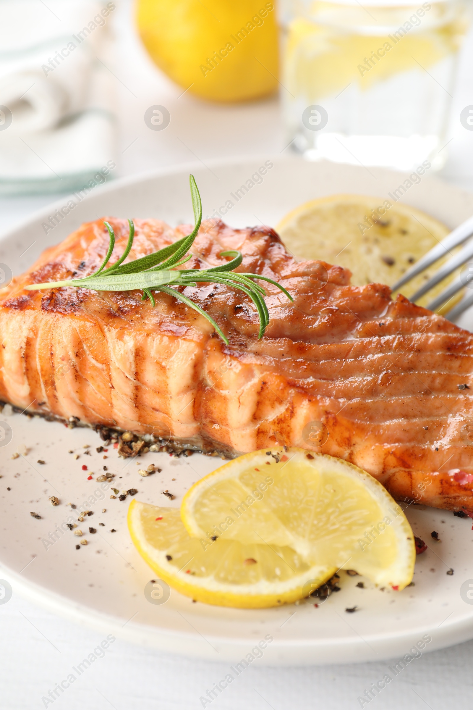 Photo of Delicious grilled salmon fillet served on white table, closeup