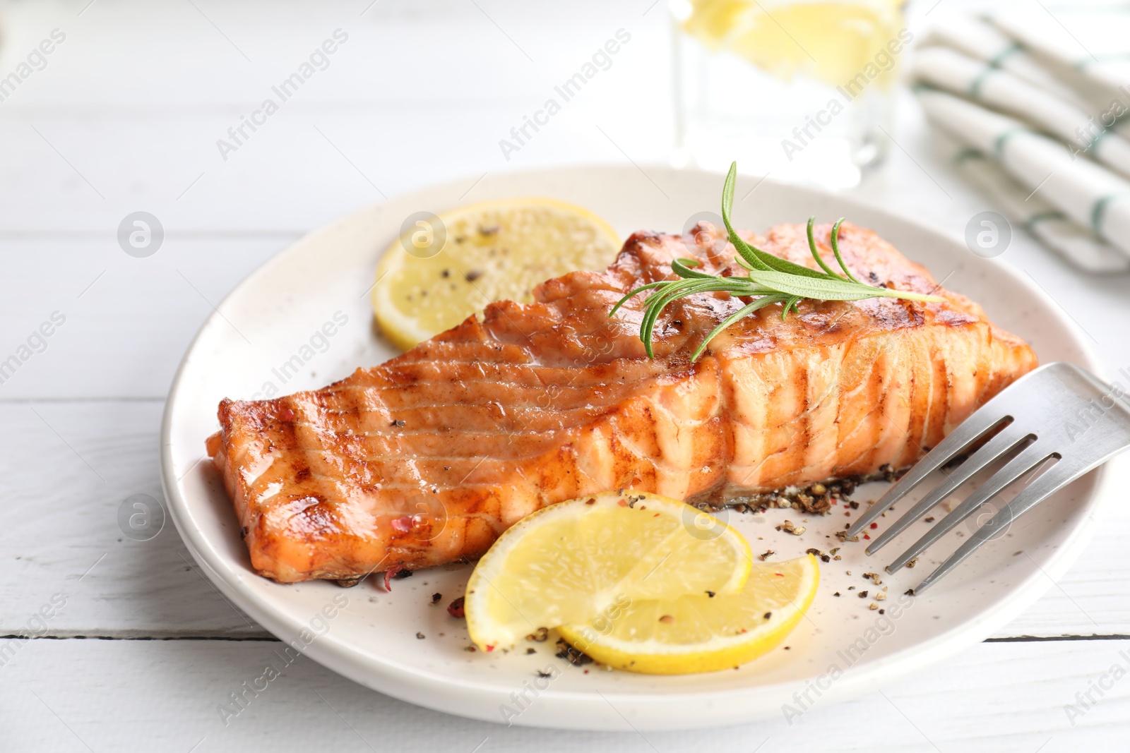 Photo of Delicious grilled salmon fillet served on white wooden table, closeup