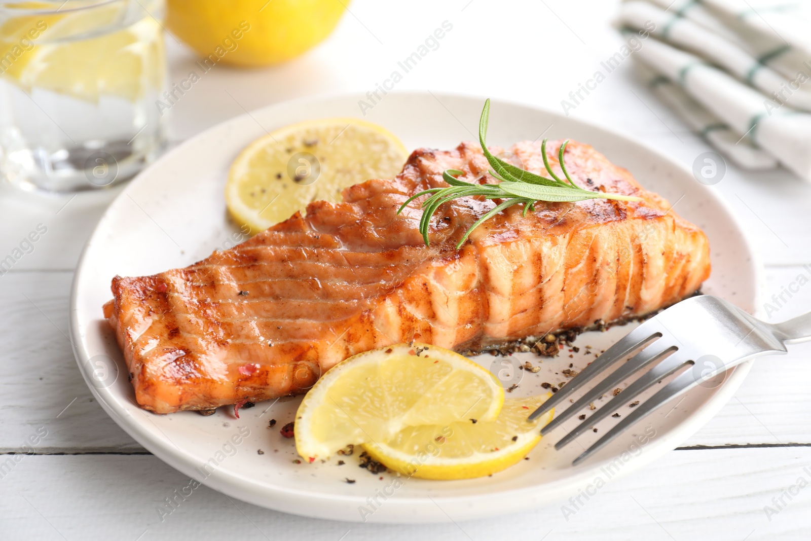 Photo of Delicious grilled salmon fillet served on white wooden table, closeup