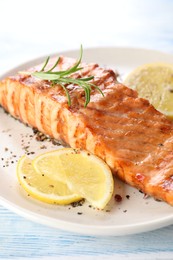 Delicious grilled salmon fillet served on light blue wooden table, closeup