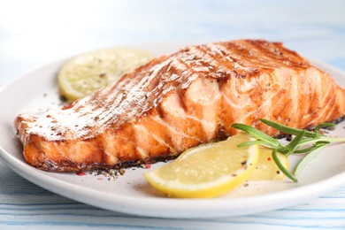 Delicious grilled salmon fillet served on light blue wooden table, closeup