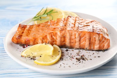 Delicious grilled salmon fillet served on light blue wooden table, closeup